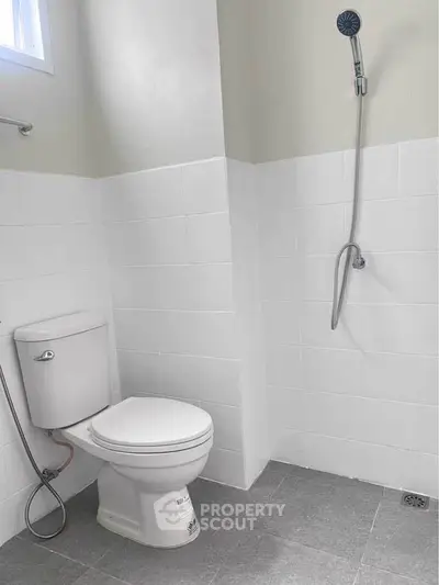 Modern bathroom with white tiles and shower, featuring a sleek toilet design.