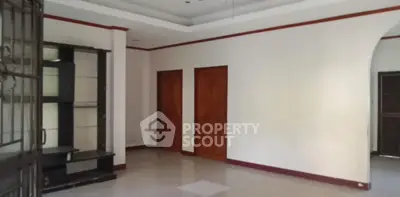 Spacious unfurnished living room with elegant wooden doors and tiled flooring.