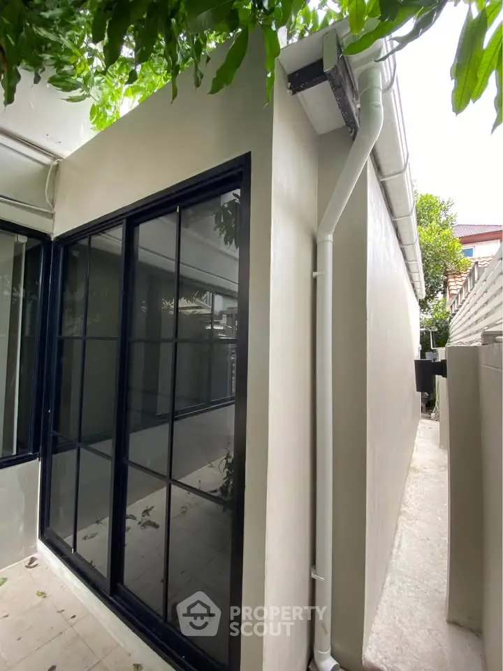 Modern exterior view of a sleek building with large glass windows and lush greenery.