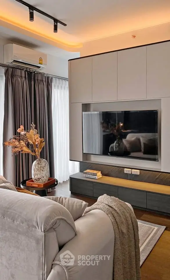 Modern living room with sleek TV setup and cozy decor, featuring elegant lighting and plush seating.