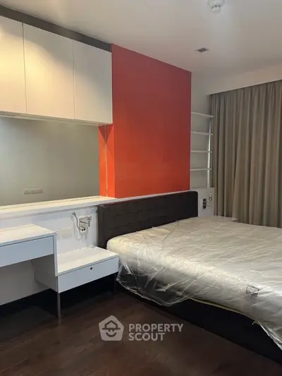 Modern bedroom with stylish red accent wall and sleek furnishings.