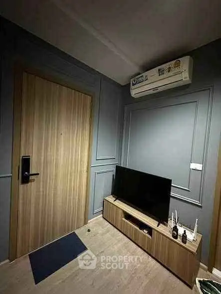 Modern living room with sleek wooden door and stylish TV stand under air conditioning unit.