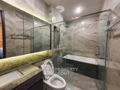 Luxurious modern bathroom with marble tiles and glass shower enclosure.