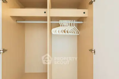 Spacious wooden wardrobe with hangers in modern apartment