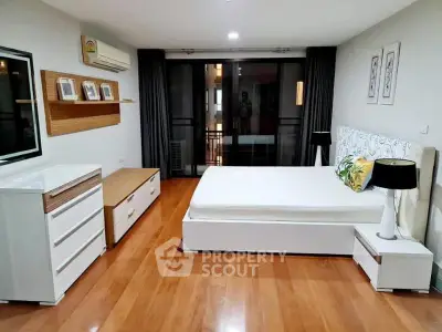 Spacious modern bedroom with elegant decor and wooden flooring, featuring a large bed and stylish furniture.