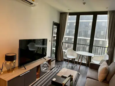 Modern living room with balcony, stylish furniture, and large TV in a high-rise apartment.