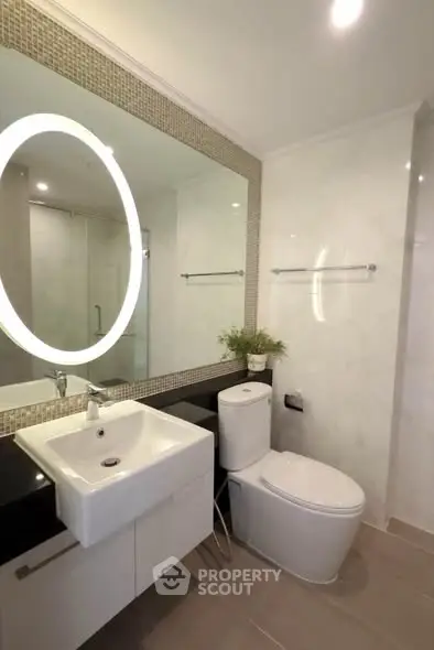Modern bathroom with sleek fixtures and illuminated mirror in a contemporary home.