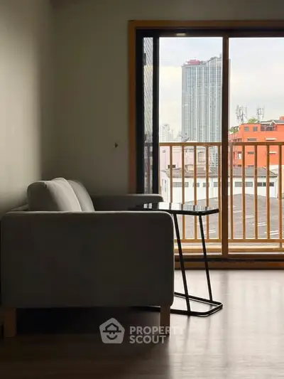 Modern living room with cozy sofa and city view from balcony.