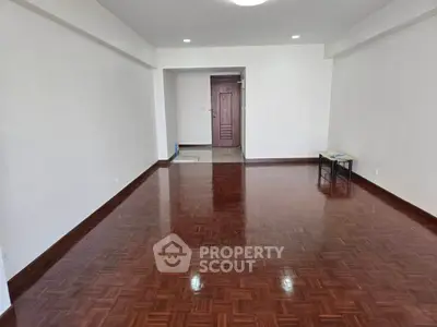 Spacious empty room with polished wooden floors and white walls, ready for customization.