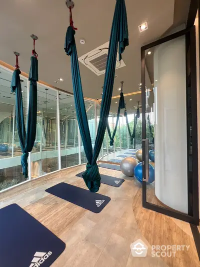 Modern gym with aerial yoga setup and exercise balls in luxury building