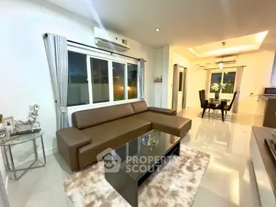 Modern living room with sleek brown sofa and dining area, featuring elegant decor and ambient lighting.