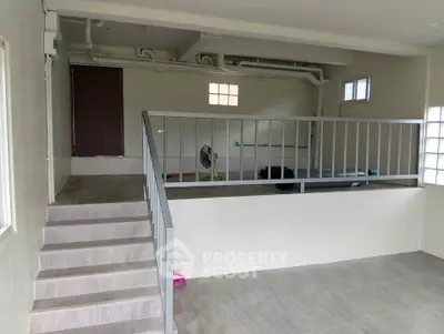 Spacious interior with elevated platform and modern railing, ideal for versatile use.