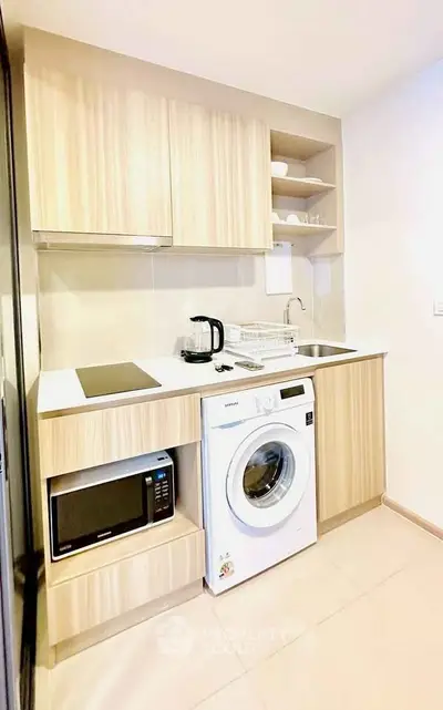 Modern compact kitchen with washing machine and microwave in stylish apartment