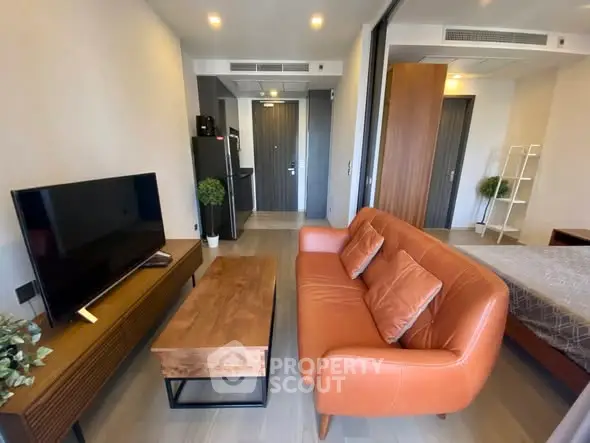 Modern studio apartment with stylish living area and cozy bedroom, featuring a sleek TV setup and contemporary furniture.