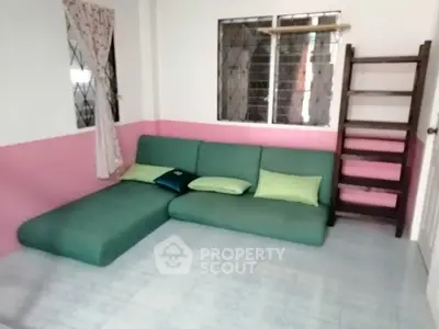 Cozy living room with green sectional sofa and pink accent wall