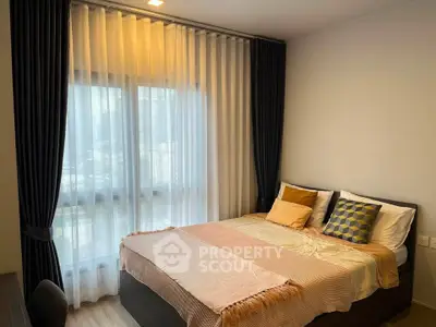 Cozy bedroom with stylish decor and large window with elegant curtains