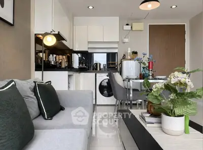 Modern living room with sleek kitchen, cozy sofa, and stylish decor in a compact apartment.