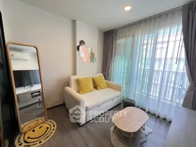 Chic living room with cozy sofa, stylish decor, and natural light through large windows.