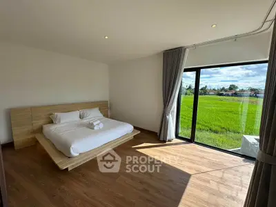 Spacious bedroom with large window offering stunning green field view