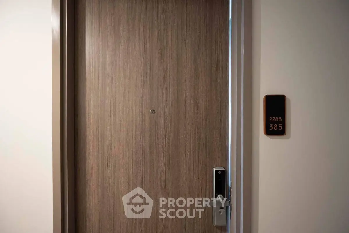 Modern apartment door with electronic lock and room number 385, showcasing secure entry.