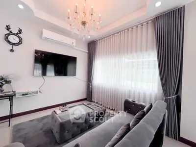 Luxurious living room with elegant chandelier and plush gray furniture, perfect for modern comfort and style.