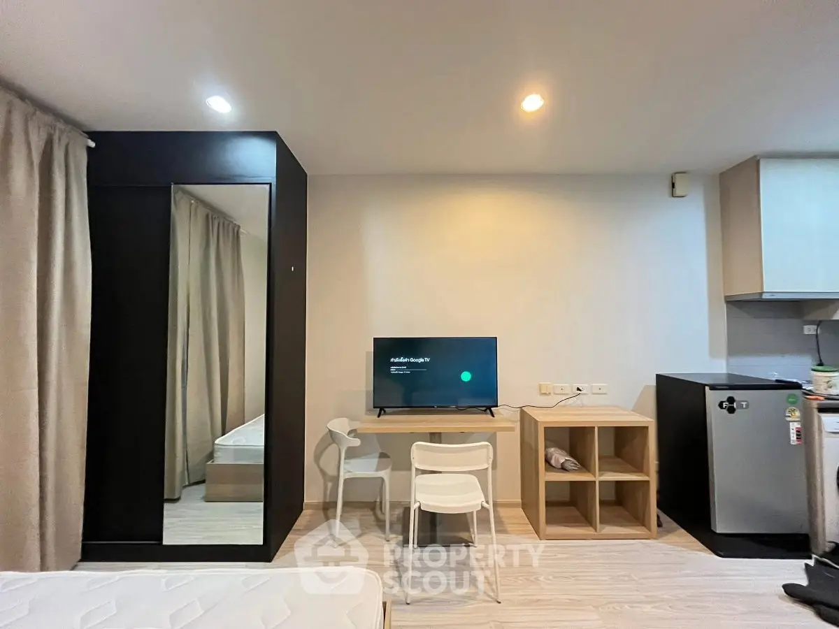 Modern studio apartment with sleek furniture and compact kitchen area, perfect for urban living.