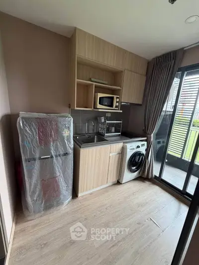 Modern compact kitchen with appliances and balcony access in stylish apartment.