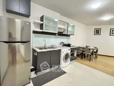 Modern kitchen with sleek appliances and dining area in open layout apartment.