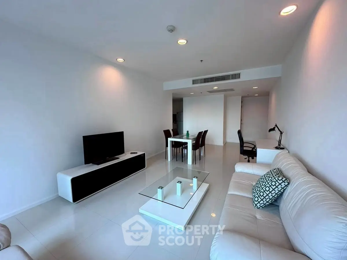 Spacious modern living room with sleek white furniture and elegant decor in a luxury apartment.