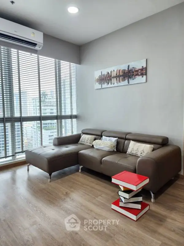Modern living room with city view, featuring sleek brown sofa and stylish decor.