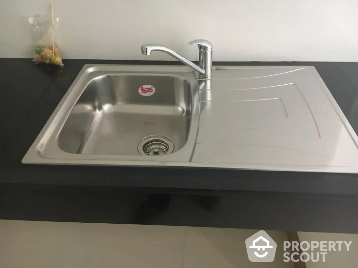 Modern stainless steel kitchen sink with sleek black countertop, perfect for contemporary home design.