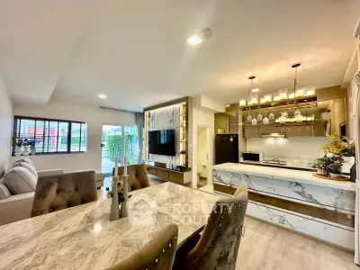 Luxurious open-plan living room and kitchen with elegant marble finishes and modern lighting.