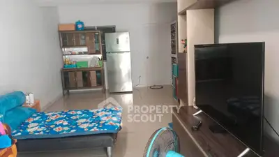 Spacious living room with modern kitchen and large TV, perfect for cozy family gatherings.