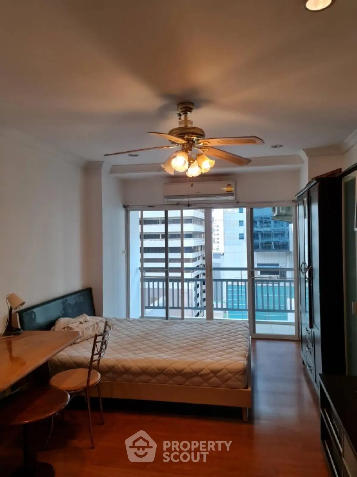 Spacious bedroom with city view and ceiling fan in modern apartment