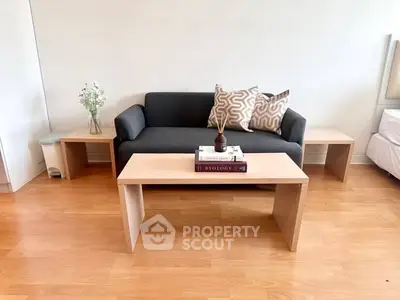 Modern living room with sleek black sofa, wooden coffee table, and stylish decor accents.