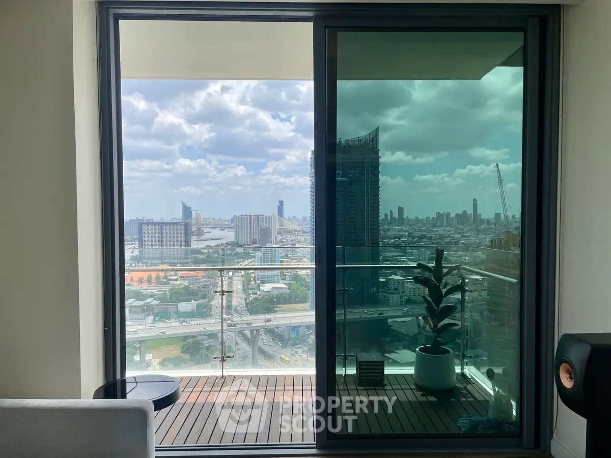 Stunning city view from modern apartment balcony with glass railing and cozy seating area.