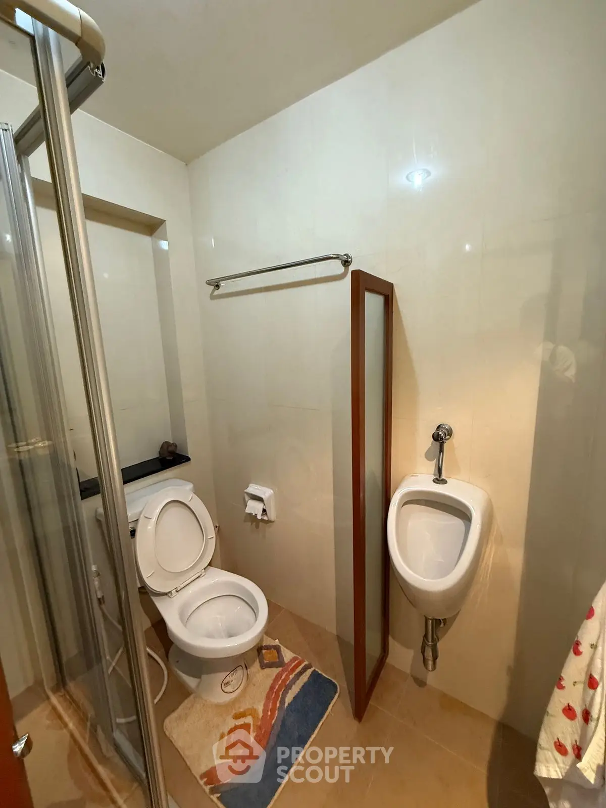 Compact bathroom with toilet, urinal, and shower in modern apartment.