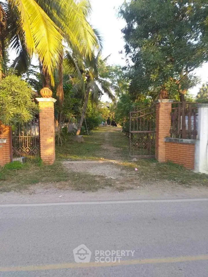 Charming entrance with brick pillars and lush greenery, perfect for a serene residential property.
