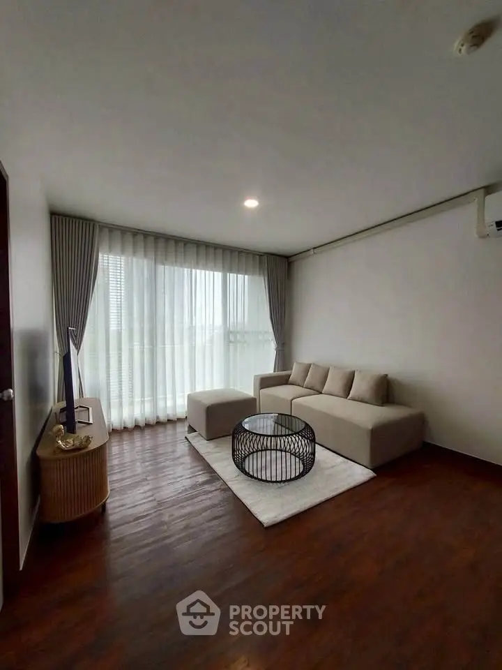 Modern living room with elegant sofa and large window, perfect for relaxation and natural light.