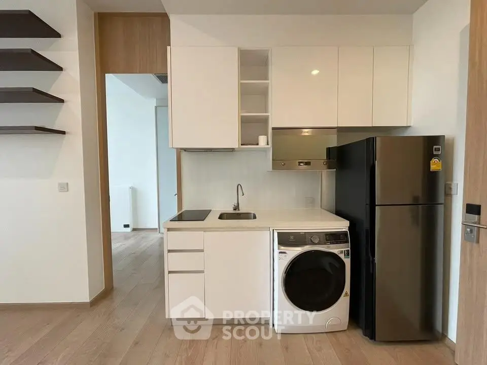 Modern kitchen with sleek cabinetry, integrated appliances, and wooden flooring in a contemporary apartment.