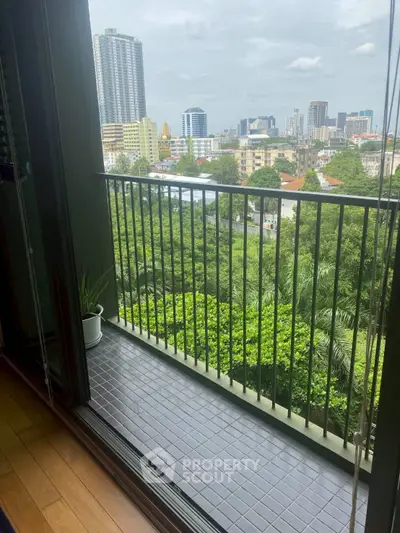 Stunning cityscape view from a cozy balcony with lush greenery and urban skyline.