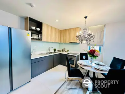 Modern kitchen with sleek cabinetry, stainless steel appliances, and elegant dining area with chandelier.