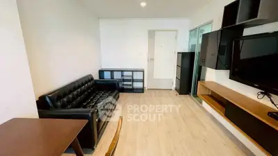 Modern living room with sleek black leather sofa and wall-mounted TV in a stylish apartment.