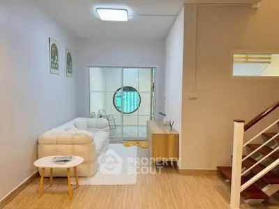 Modern living room with stylish decor and cozy seating area, featuring a unique circular window design.
