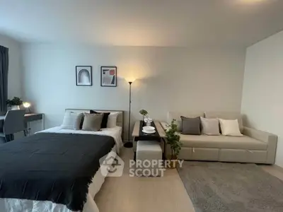 Modern studio apartment with cozy bed, stylish sofa, and chic decor in open layout.