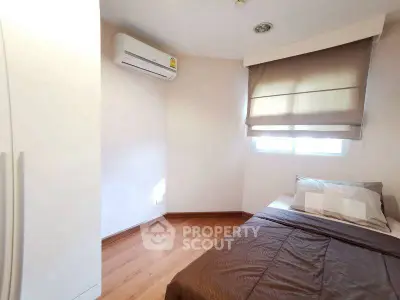 Cozy bedroom with wooden flooring and air conditioning, perfect for relaxation.