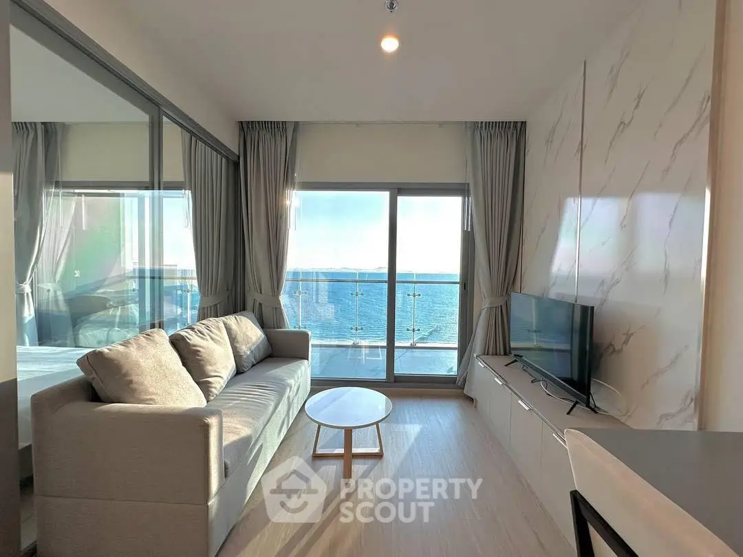 Modern living room with ocean view, sleek furniture, and floor-to-ceiling windows.