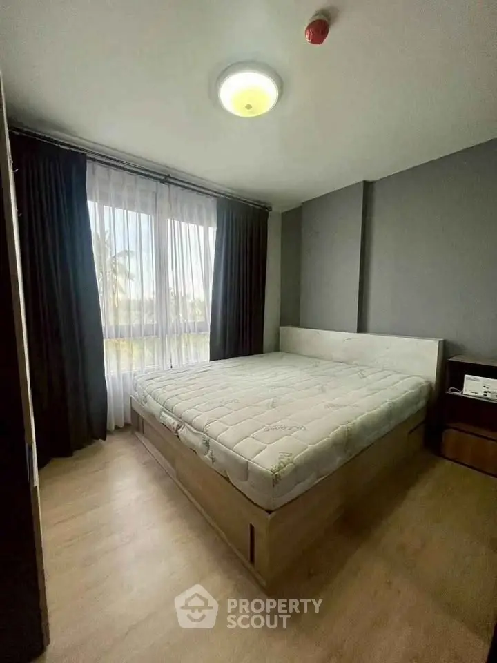 Cozy bedroom with large window and modern decor, perfect for relaxation.