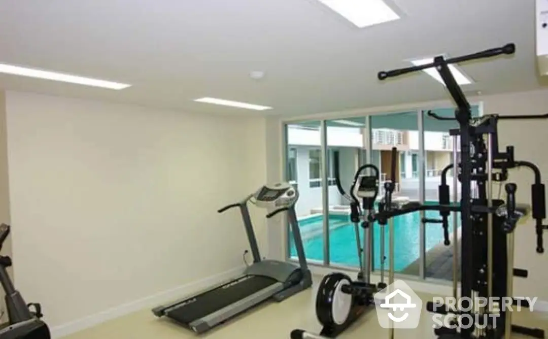 Spacious home gym with modern equipment and a view of the outdoor pool, perfect for a fitness enthusiast's luxury property.