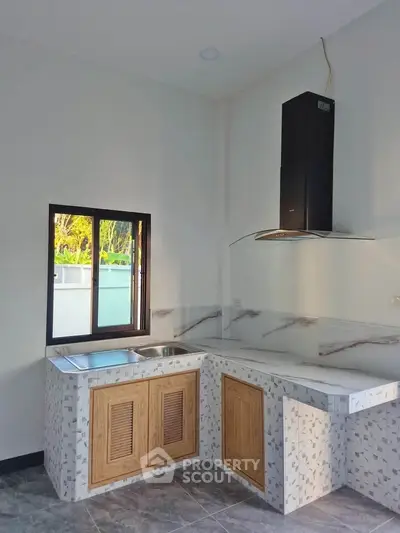 Modern kitchen with sleek design, featuring a marble countertop and wooden cabinets, perfect for culinary enthusiasts.